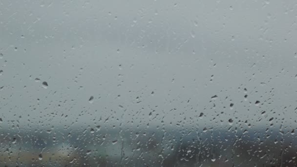 Крупный план серого дождливого стекла с капельками воды — стоковое видео