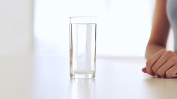 Кадри жінки розчиняють таблетку в склянці води — стокове відео