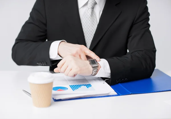 Businessman with graphs pointing at watch — Stock Photo, Image