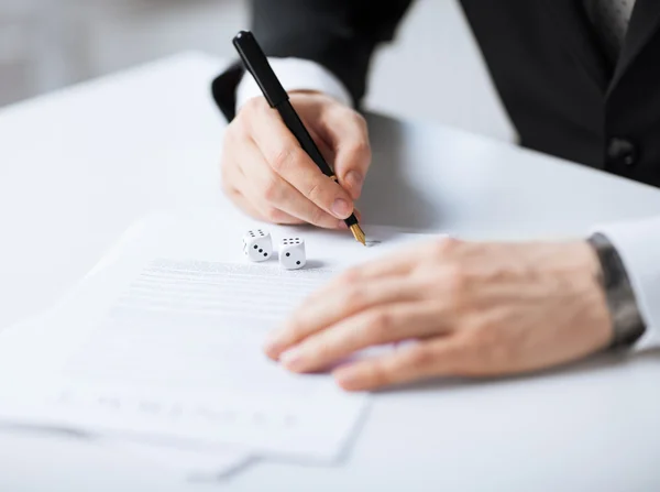 Hombre manos con juego dados firma contrato — Foto de Stock