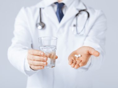 Doctor hands giving white pills and glass of water clipart
