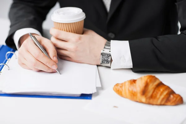 Uomo d'affari con caffè che scrive qualcosa — Foto Stock