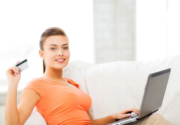 Mulher com laptop mostrando cartão de crédito em casa — Fotografia de Stock