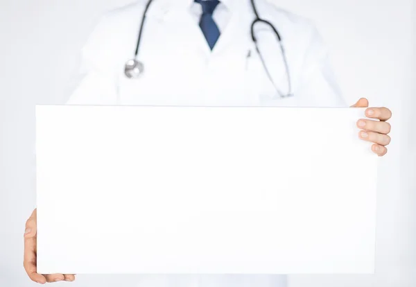 Doctor sosteniendo banner blanco en blanco — Foto de Stock