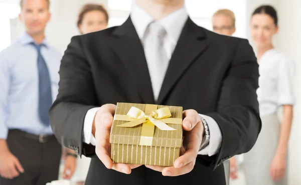 Мужские руки держат подарочную коробку в офисе — стоковое фото