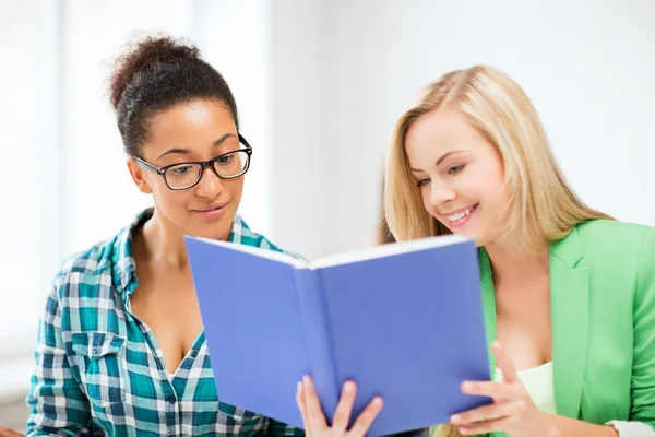 Lachende student meisjes lezen boek op school — Stockfoto