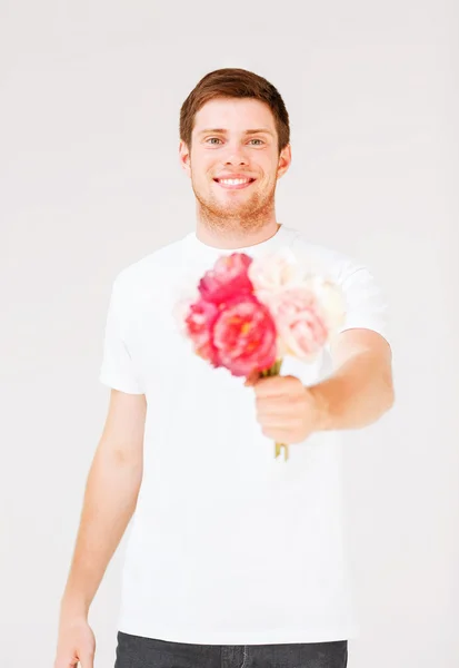 Young man holding bouquet of flowers — Stock Photo, Image
