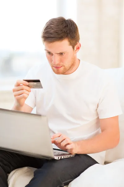 Uomo con computer portatile e carta di credito a casa — Foto Stock