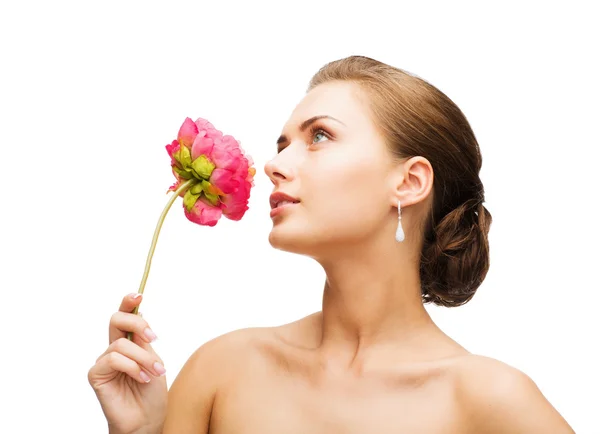 Vrouw oorbellen dragen en ruiken bloem — Stockfoto