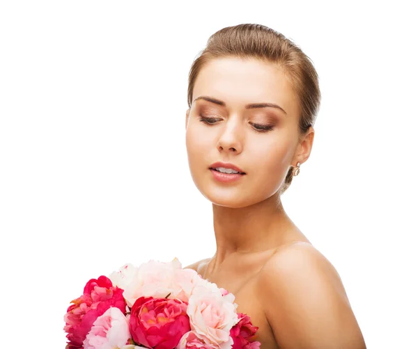 Mujer usando pendientes y sosteniendo flores — Foto de Stock