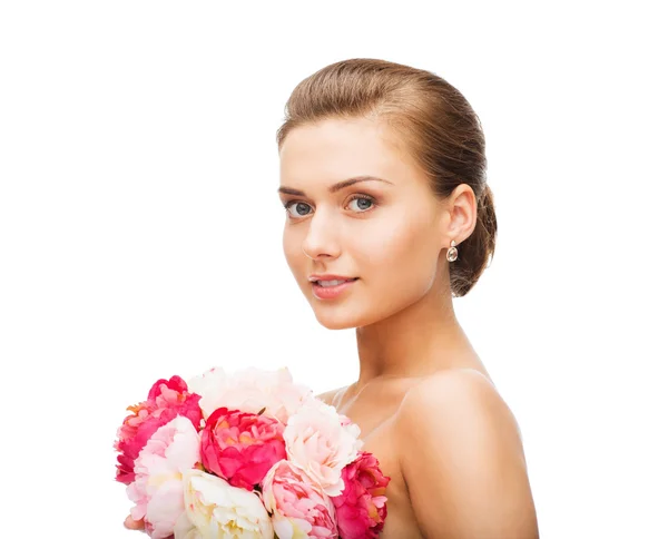 Mujer usando pendientes y sosteniendo flores — Foto de Stock