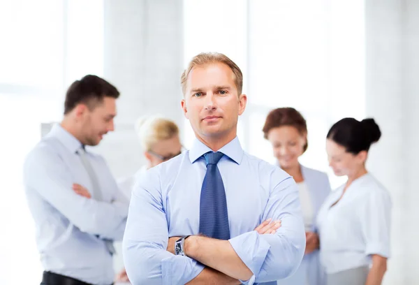 Hombre de negocios guapo con equipo en la oficina — Foto de Stock