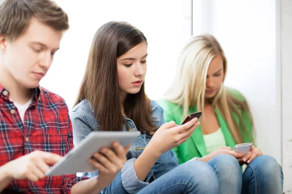 Students looking into devices at school — Stock Photo, Image