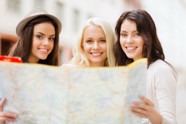 Beautiful girls looking into tourist map in city clipart