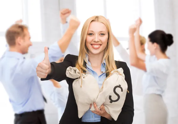 Empresária com sacos de dinheiro mostrando polegares para cima — Fotografia de Stock