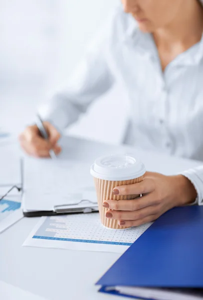 Kvinna med kaffe fylla i tomma papper — Stockfoto