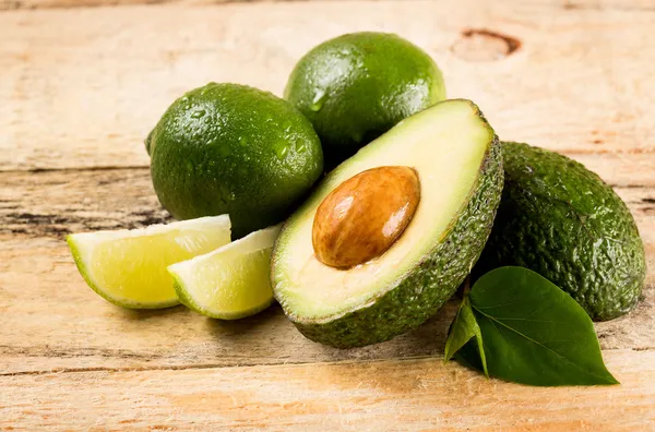 Aguacate y limas sobre fondo de madera — Foto de Stock