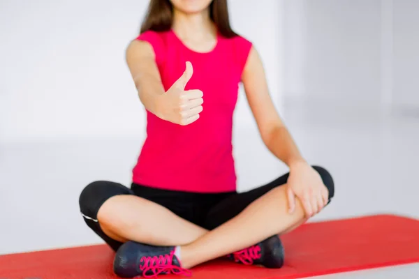 Girl sitting in lotus position with thumbs up Stock Picture