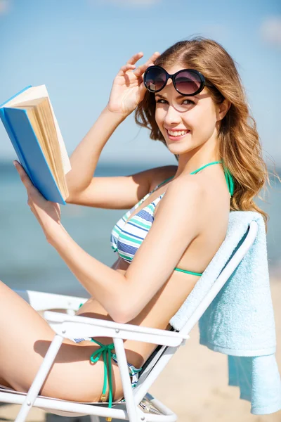 Tjej läser bok på stranden stolen — Stockfoto