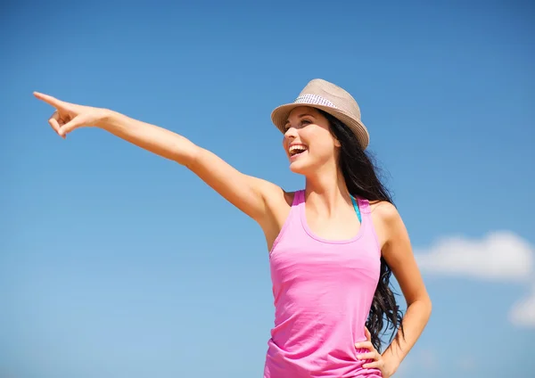 Girl in hat showing direction on the beach — Stock Photo, Image