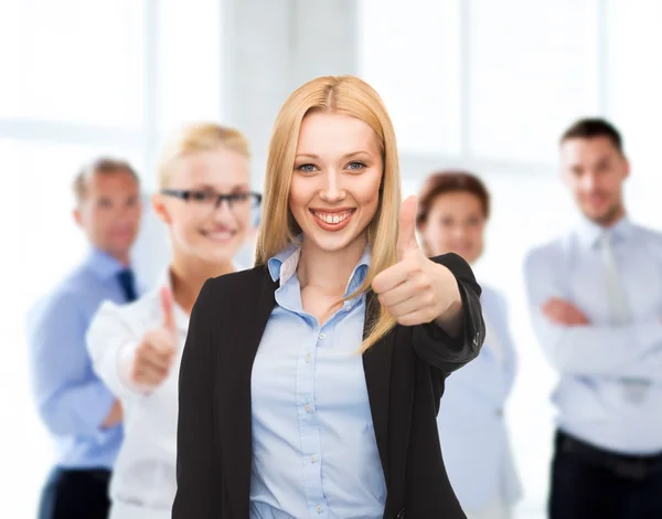 Businesswoman showing thumbs up in office Stock Photo