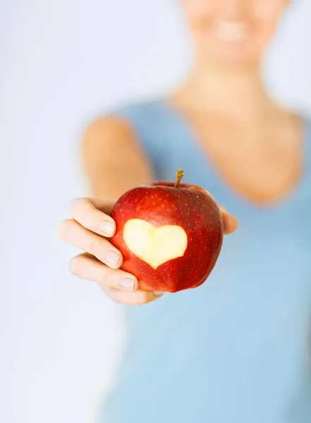 Woman hand holding red apple with heart shape — Stock Photo, Image