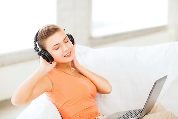 Mulher com fones de ouvido e laptop em casa — Fotografia de Stock