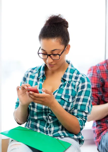 African student browsing in smartphone at school — Stock Photo, Image