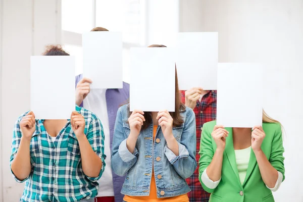 Studenten die betrekking hebben op gezichten met lege papieren — Stockfoto