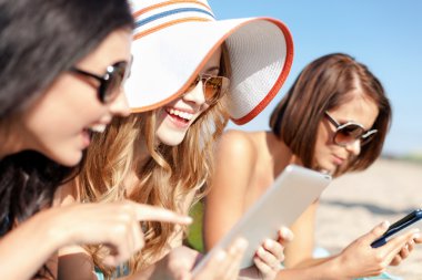 Girls with tablet pc on the beach clipart