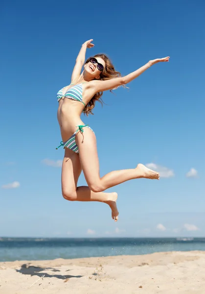 Frau im Bikini springt am Strand — Stockfoto