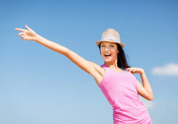 Girl in hat showing direction on the beach — Stock Photo, Image