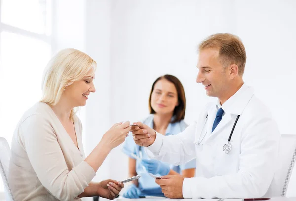 Doctor giving tablets to patient in hospital — Stock Photo, Image