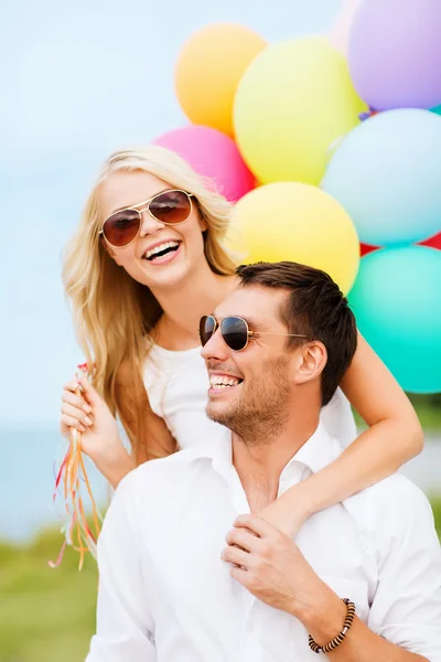 Pareja con globos de colores en la playa — Foto de Stock