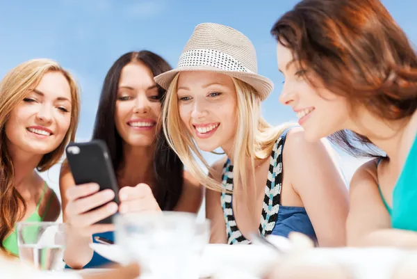 Meisjes op zoek naar smartphone in café op het strand — Stockfoto