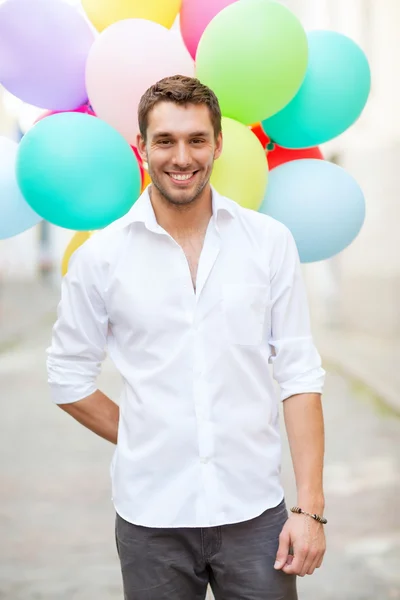 Muž s barevnými balónky ve městě — Stock fotografie