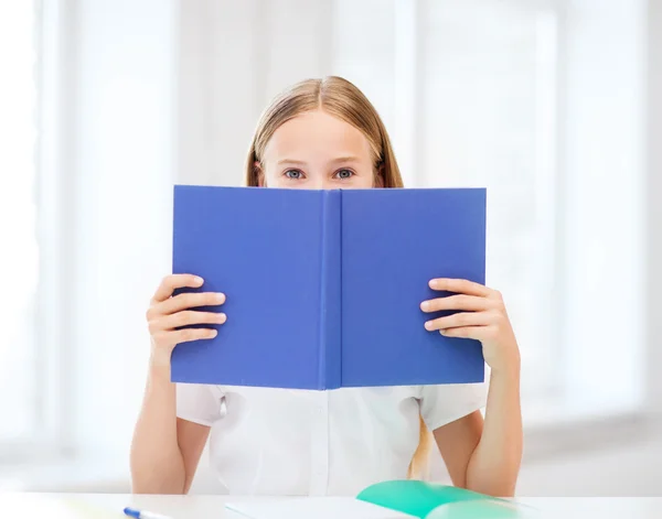 Mädchen lernt und liest Buch in der Schule — Stockfoto