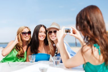 Girls taking photo in cafe on the beach clipart