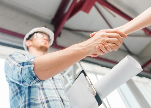 Bouwer met blauwdruk partner hand schudden — Stockfoto