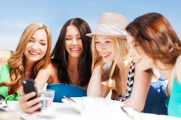 Chicas mirando el teléfono inteligente en la cafetería en la playa —  Fotos de Stock