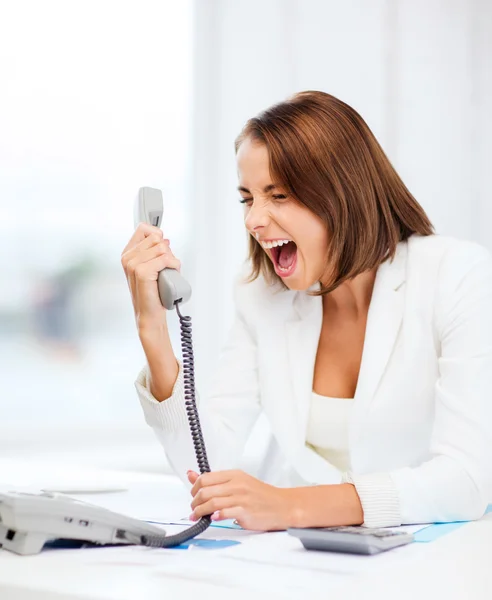Женщина, кричащая в телефон в офисе Лицензионные Стоковые Фото