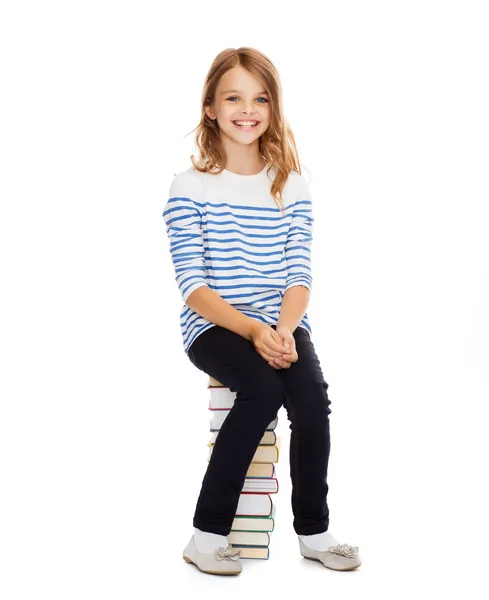 Little student girl sitting on stack of books — Stock Photo, Image