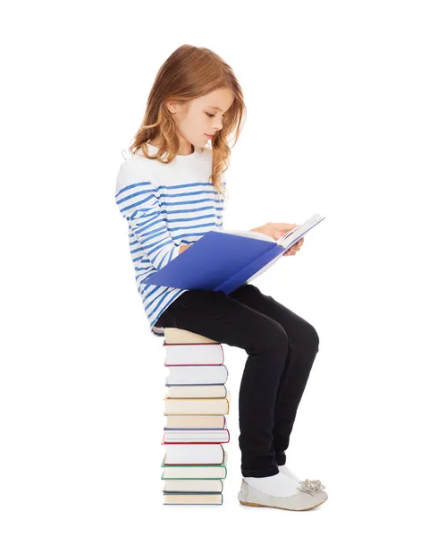 Student meisje zittend op stapel boeken — Stockfoto