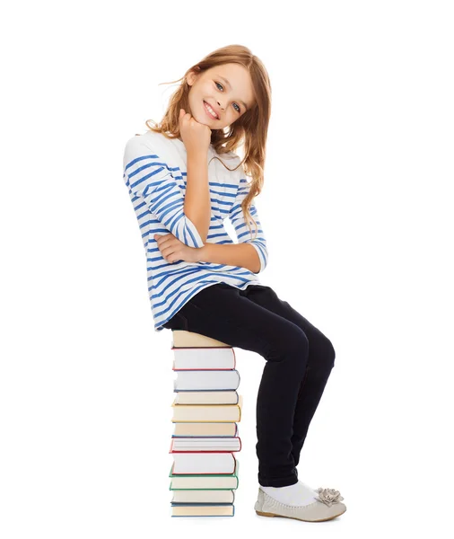 Student meisje zittend op stapel boeken — Stockfoto