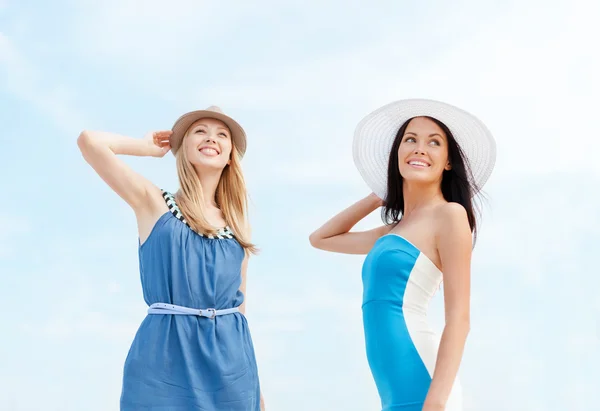 Girls in dresses with hats on the beach — Stock Photo, Image