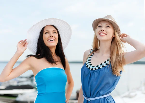 Mädchen in Kleidern mit Hüten am Strand — Stockfoto