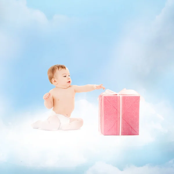 Lächelndes Baby mit Geschenk auf der Wolke — Stockfoto