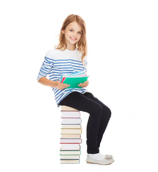 Petite étudiante assise sur une pile de livres — Photo