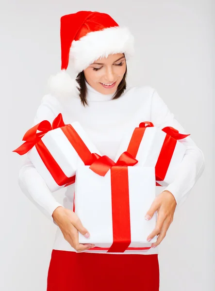 Frau mit Weihnachtsmann-Helfermütze mit vielen Geschenkboxen — Stockfoto