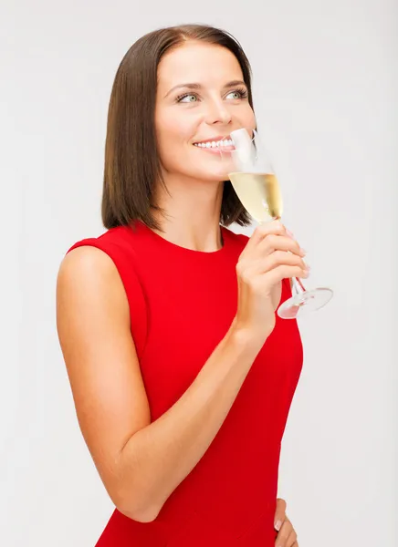 Kvinna i röd klänning med ett glas champagne — Stockfoto